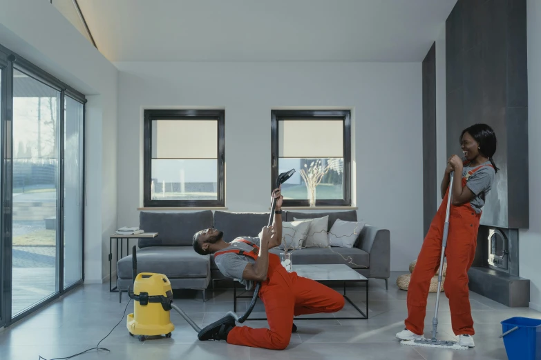 two people are vacuuming the floor in the living room