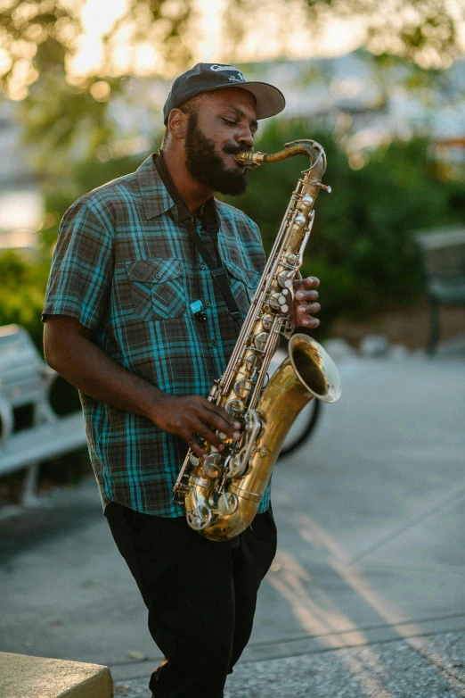 a man standing near a wall playing a saxophone