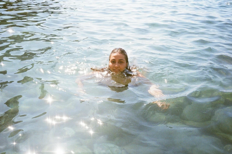 a woman swims in a body of water with lots of sunlight