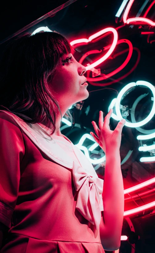 woman standing in dark room wearing a dress and lit up neon