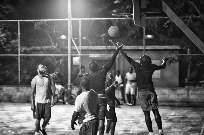 three young men playing basketball outside on a basketball court