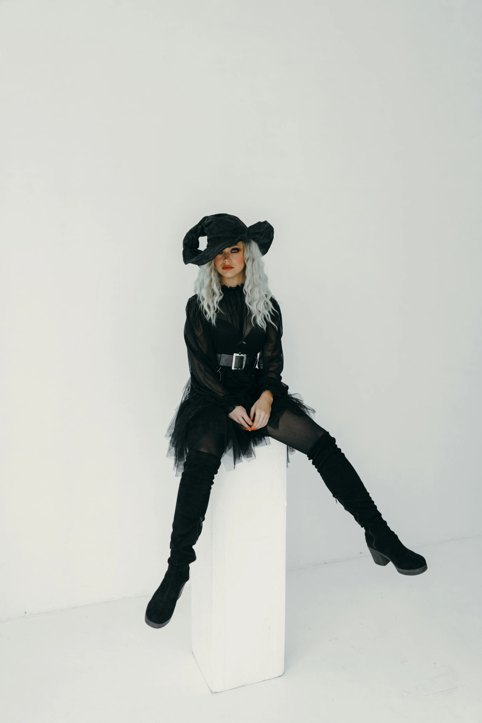 a woman sitting on a pillar wearing black