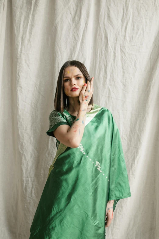 a woman in a green silk dress holding a phone