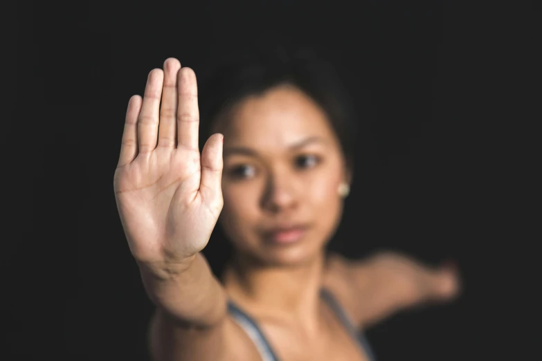 a woman standing in front of a black background holding her hand out