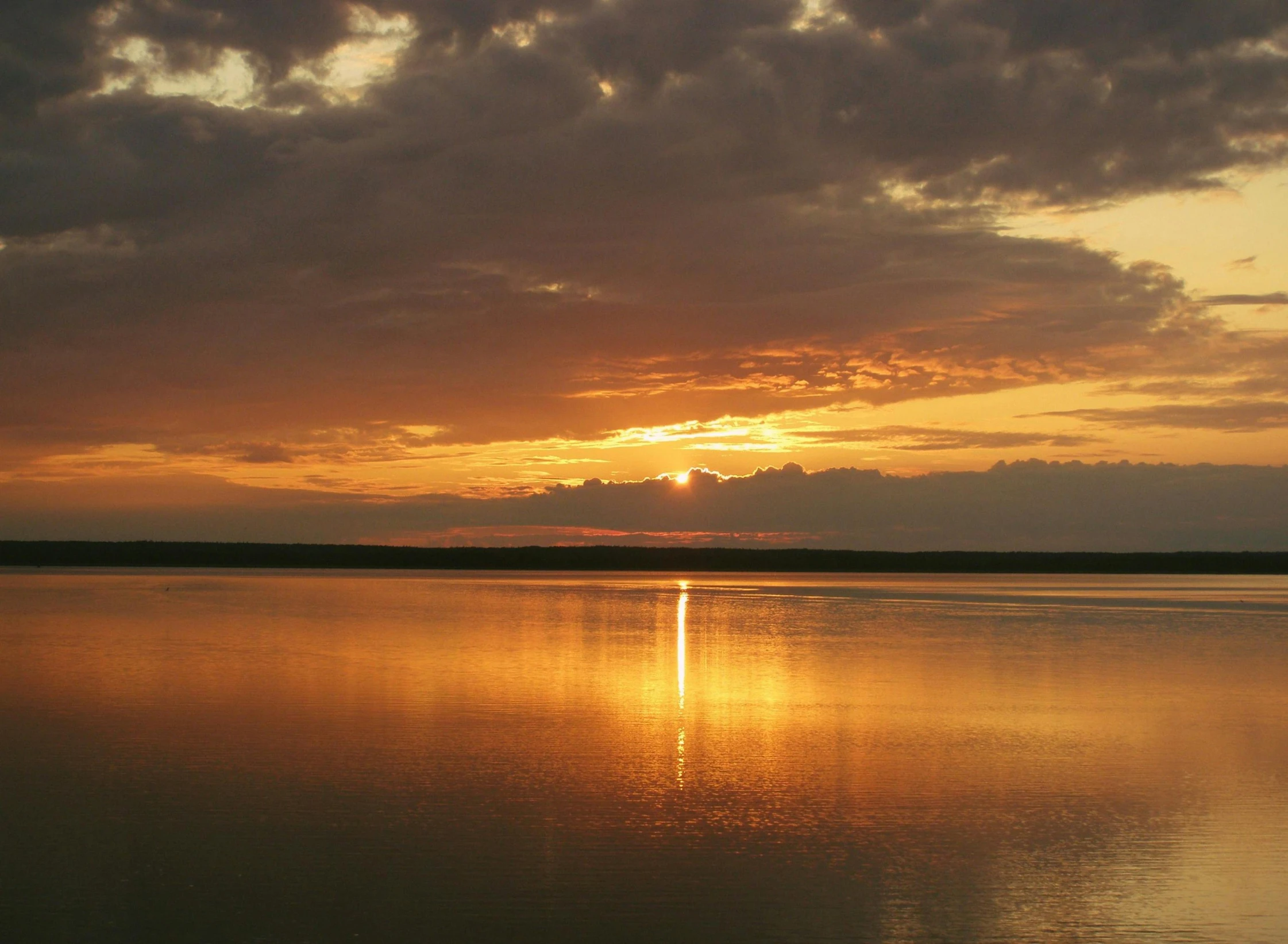 there is a calm lake with some clouds in the distance