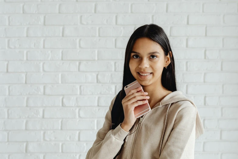 smiling woman with hooded jacket on, holding onto cell phone