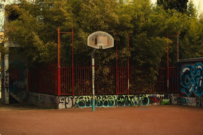 the gate of an outdoor basketball court with graffiti on it