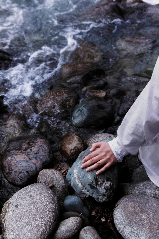 a person reaches out from beneath a rock