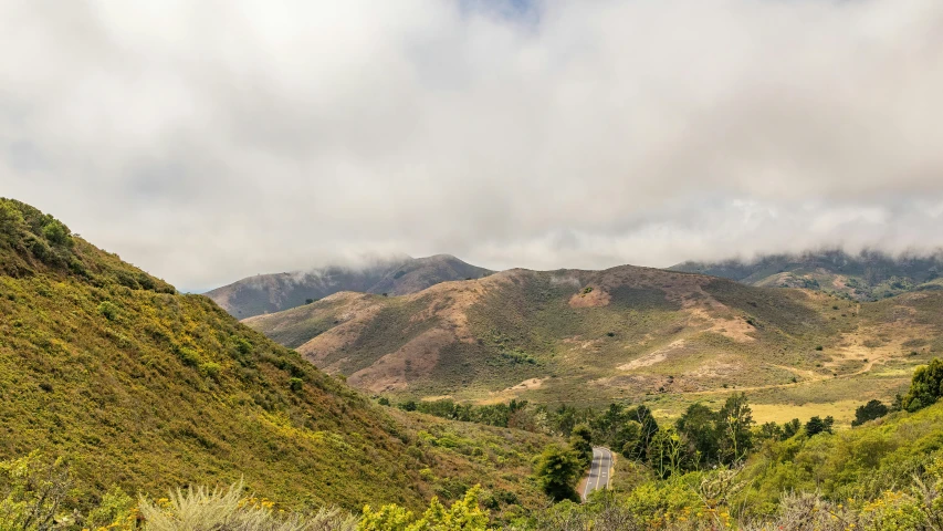 a group of mountains with clouds rolling in from the top