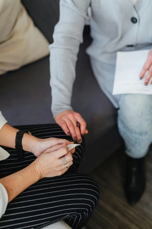 two people sitting on a couch and one holding a small white cigarette