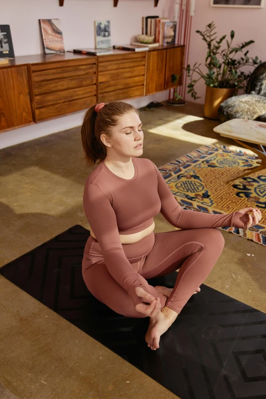 a girl is doing yoga on a black mat