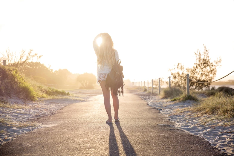 a woman walking down a country road in the sunset