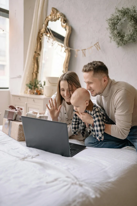 two people with a baby looking at a laptop