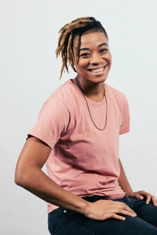 a woman with dreadlocks smiling while sitting on a chair