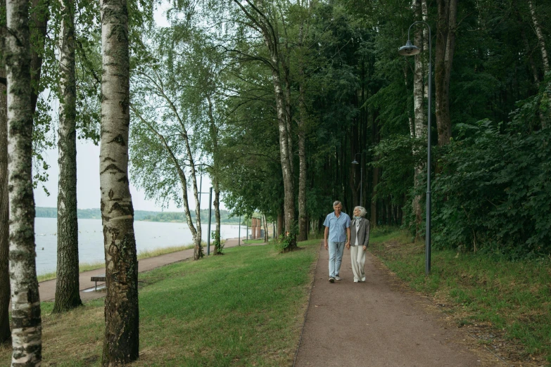 two people are walking down the path near some trees