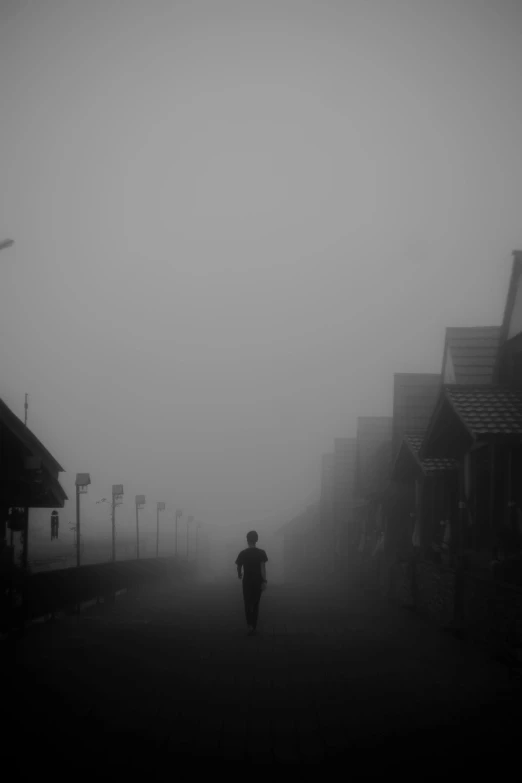 person walking on sidewalk in foggy area next to houses