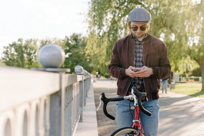 a man in a cap is holding a red bike