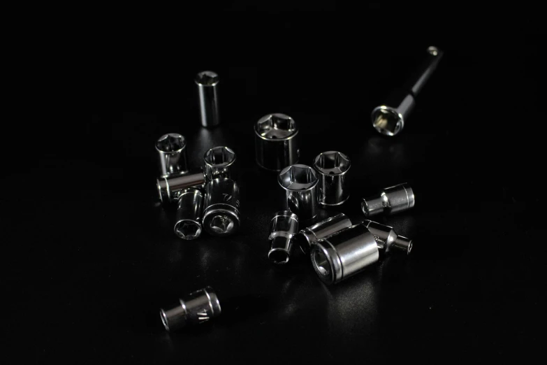 an assortment of aluminum parts on black surface