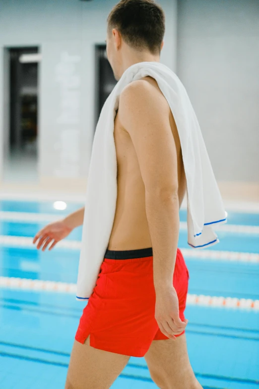 a male swimmer wearing a robe and red shorts in a swimming pool