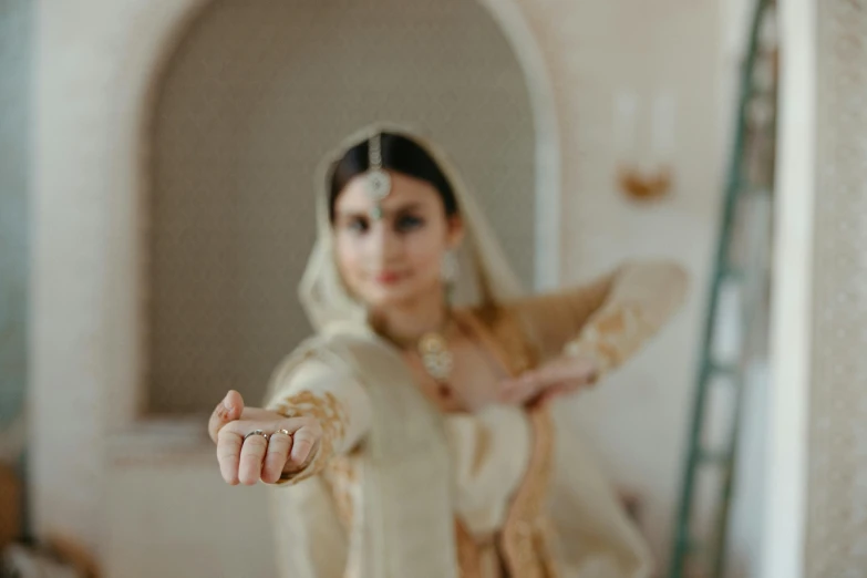 a woman with a white shawl on her head pointing to the camera