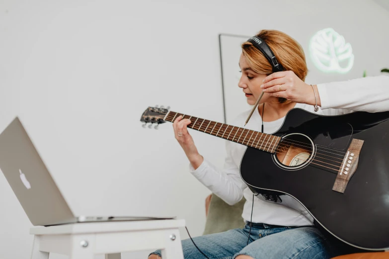 a woman sits on the couch and holds an acoustic guitar