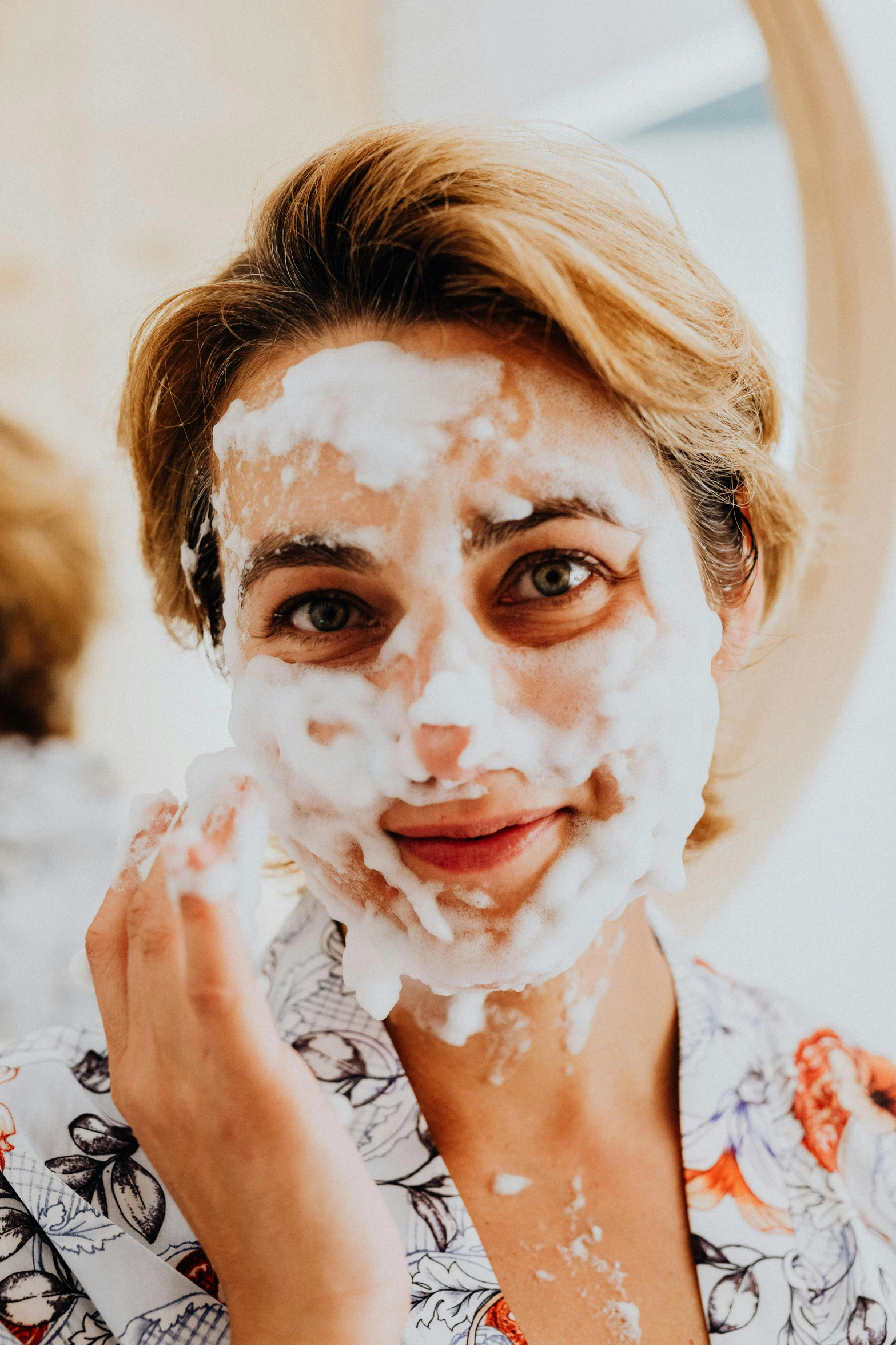 woman shaving in the morning and using a facial scrub on her face