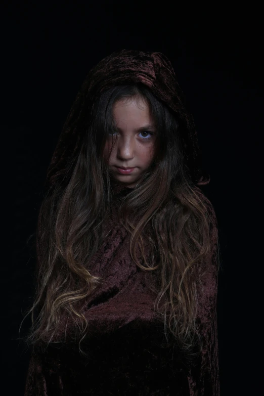 a little girl with long hair and a hood