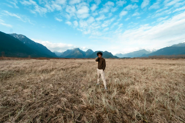 a man standing in a field of tall brown grass