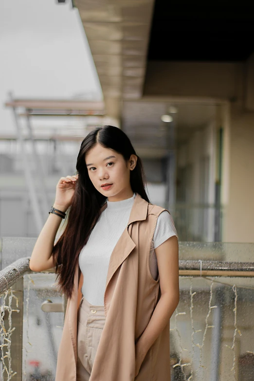 a woman with long dark hair in white shirt, light brown vest, and tan skirt