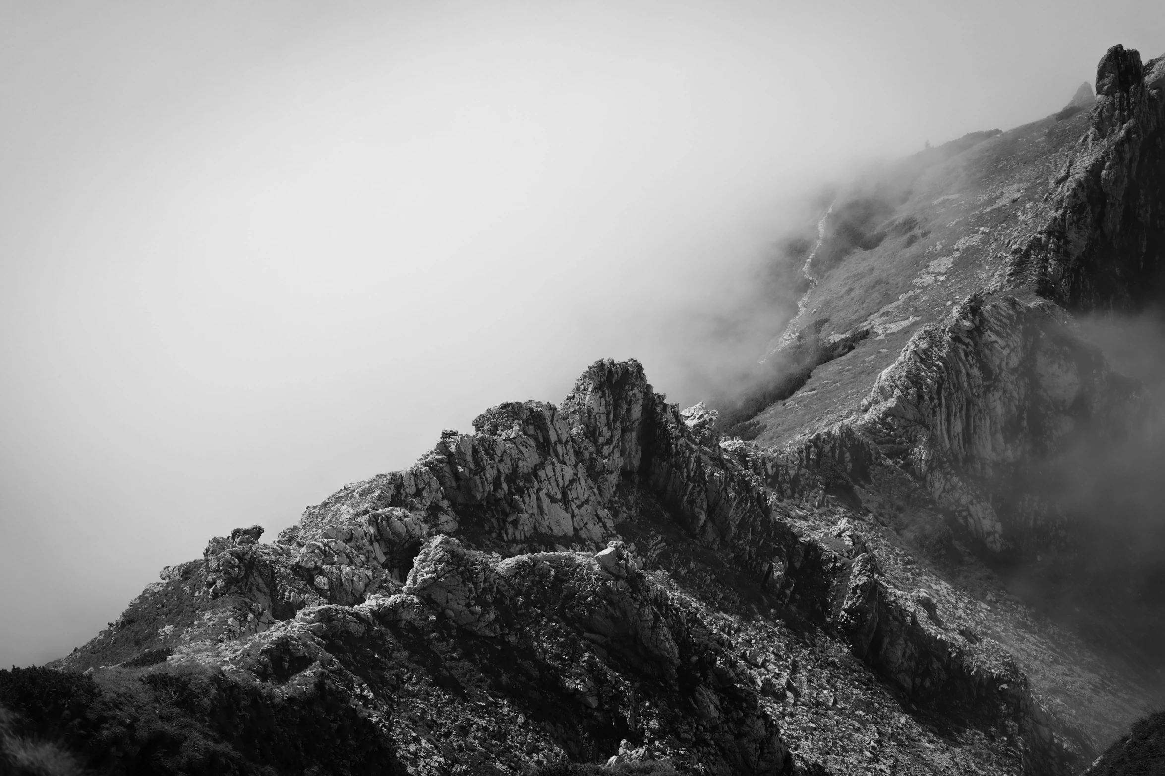 a mountain covered in fog and mist with clouds