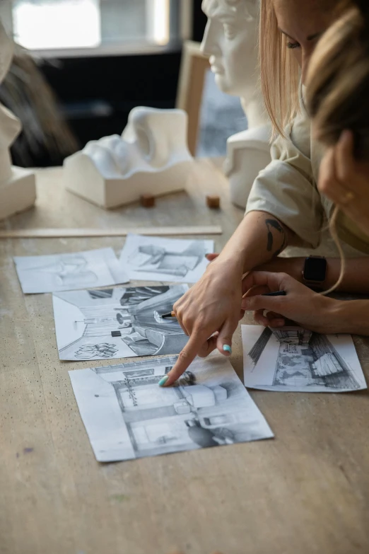 a woman sitting at a table with some drawings on it