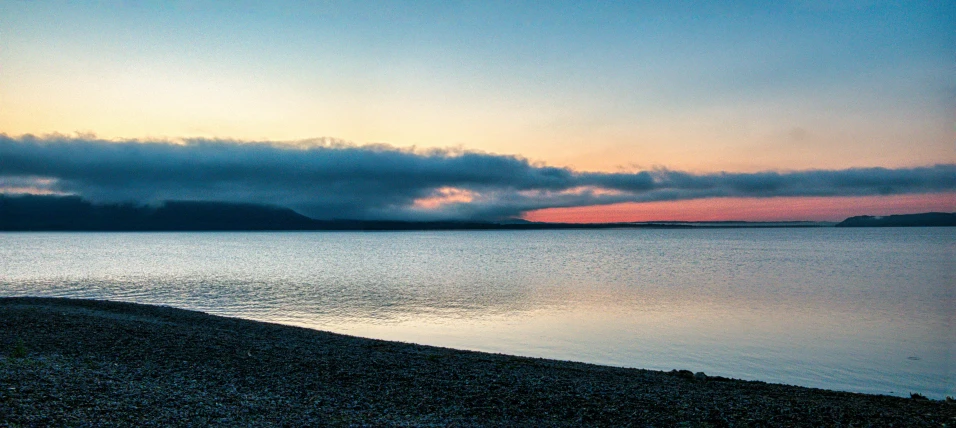 a large body of water with a hillside in the distance