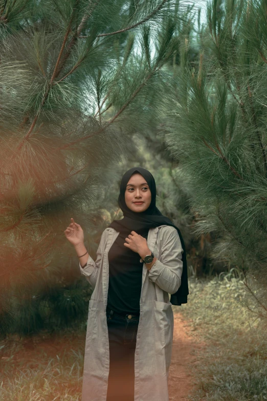 a woman is standing among the trees and bushes