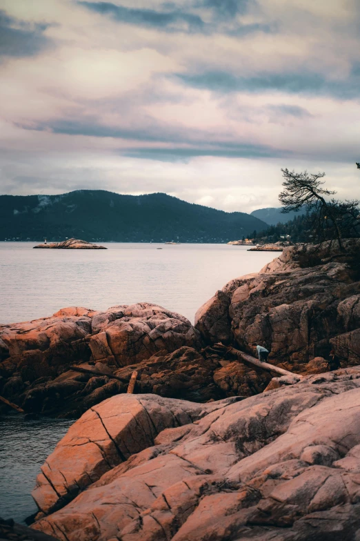 a man walking on the edge of a cliff by some water