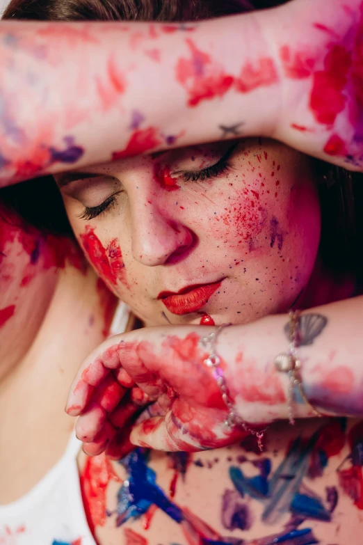 a woman covered in colors covers her face