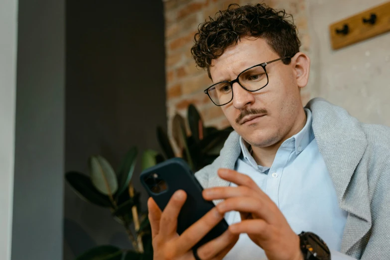 man wearing glasses looking at his cell phone