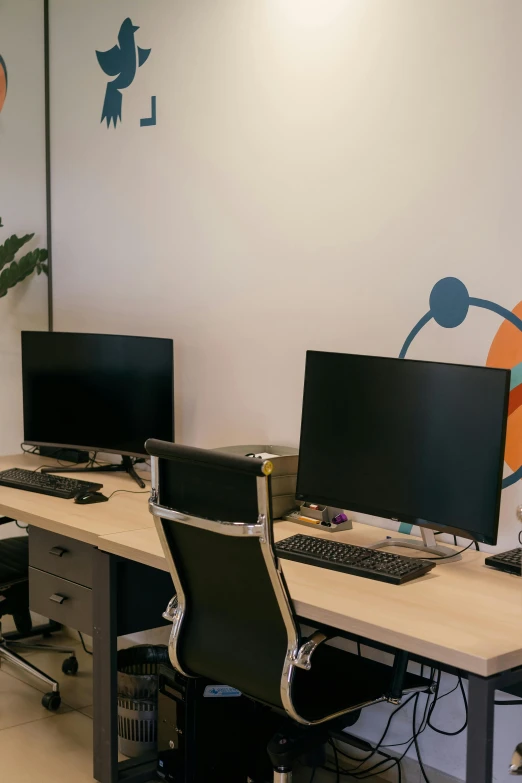 three computer screens with black chairs are lined up