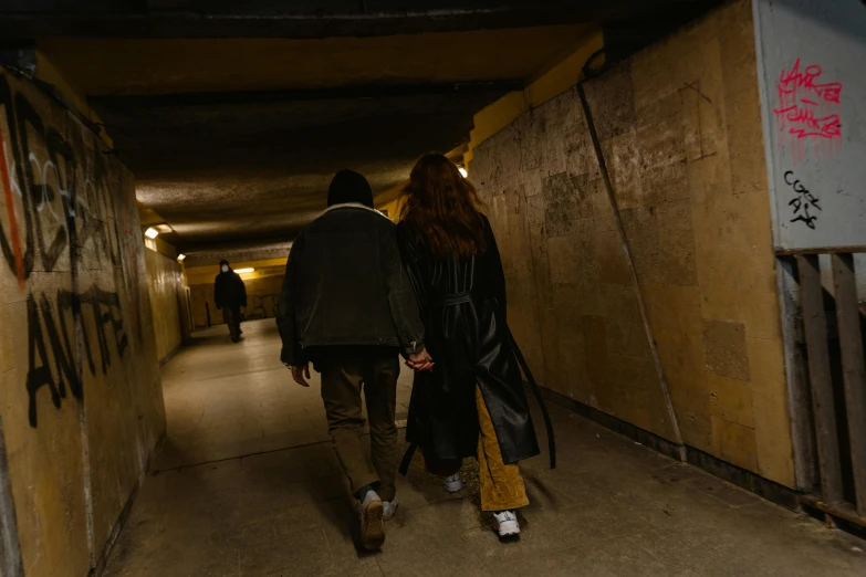 two people walking up an empty corridor with graffiti