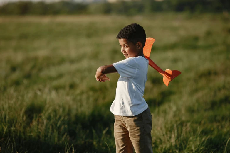a young child standing on a green field holding a plastic toy