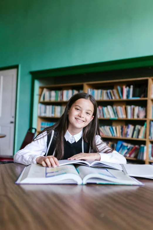 a little girl sitting at a table with a book