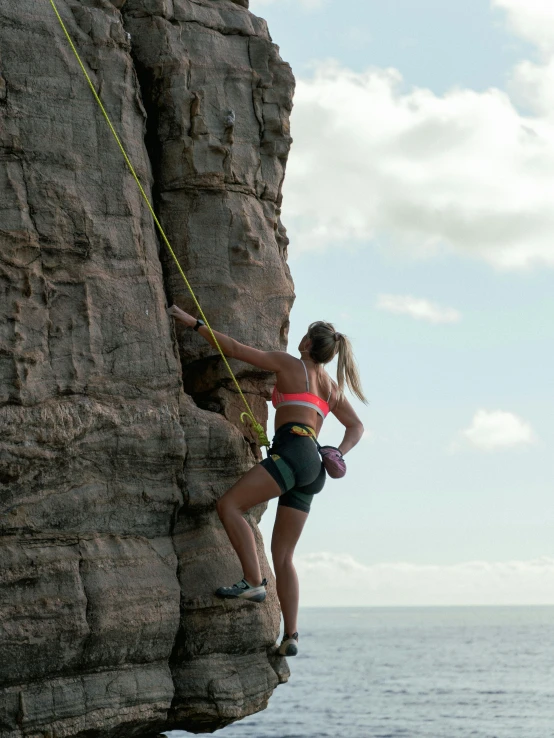 a woman standing on the side of a cliff while rock climbing