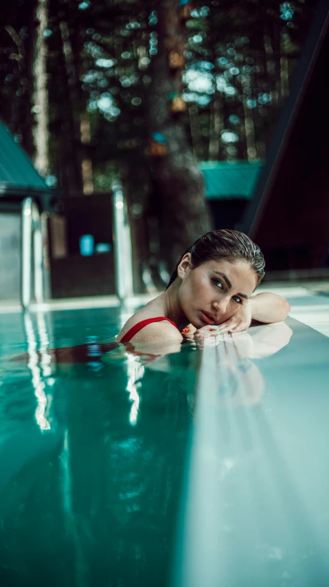 a woman with a bikini is laying on her back in a pool