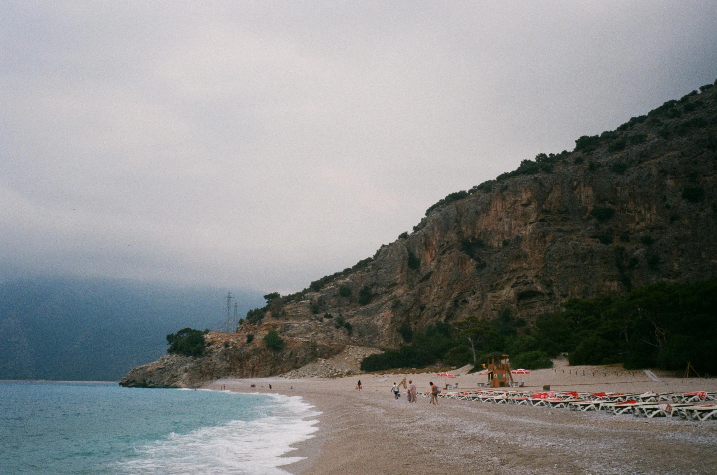 people walking along the beach on a cloudy day