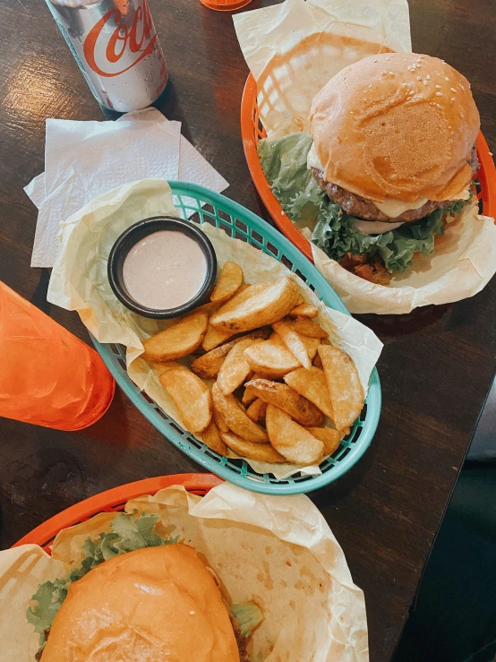 two baskets with different burgers and french fries in them