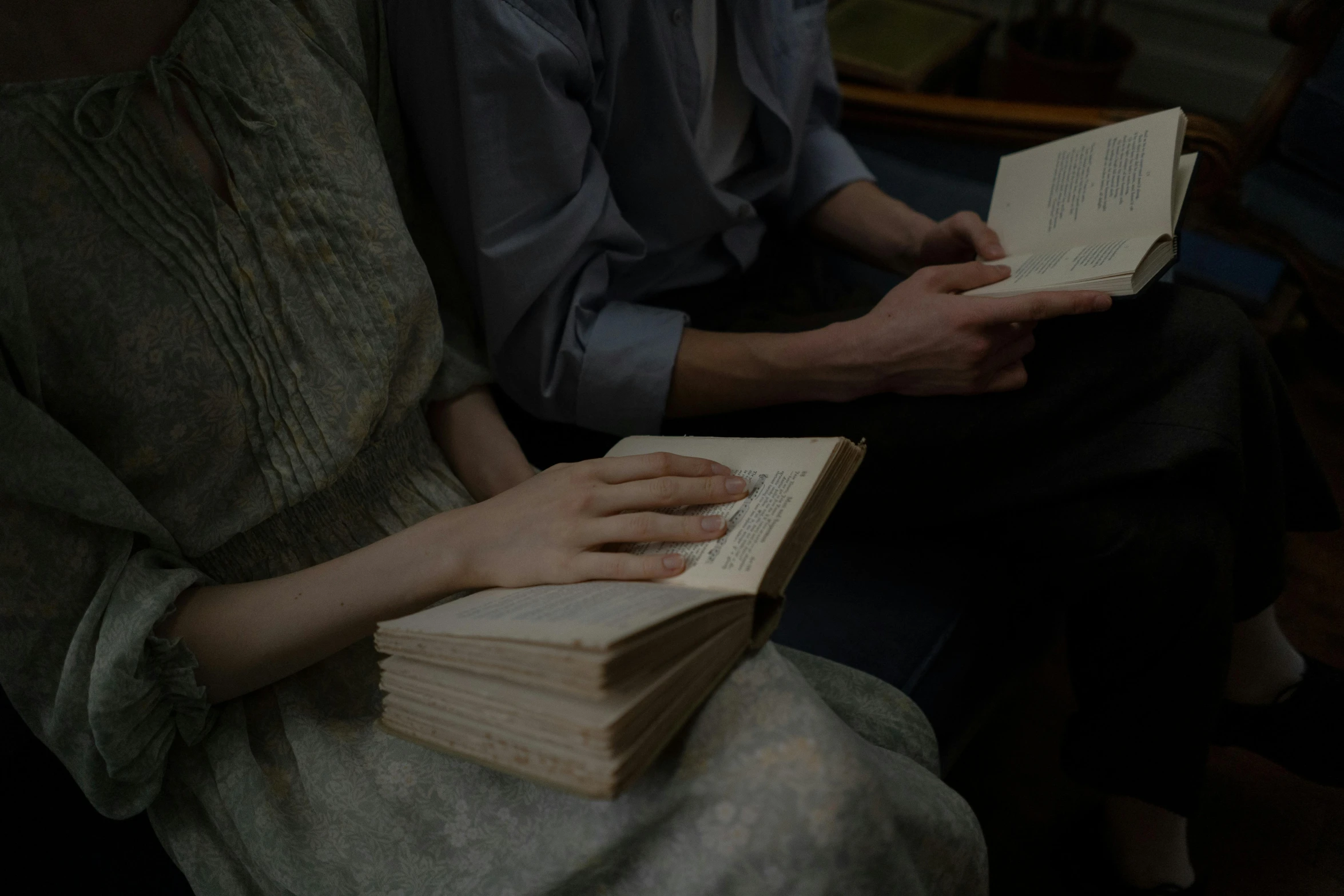 a couple of people are sitting down reading books