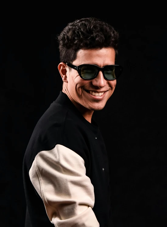 a smiling man wearing a black shirt and some shades