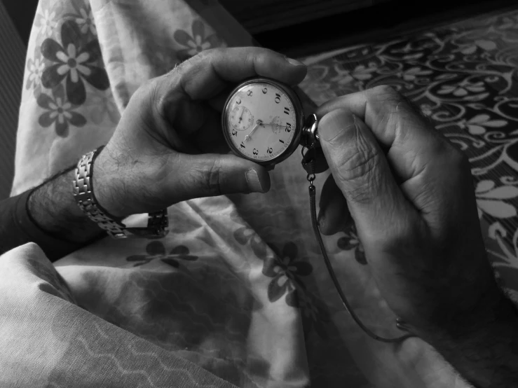 black and white pograph of an older man's hands holding a small pocket watch