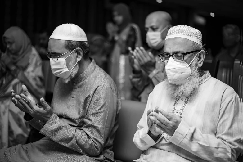 several men are sitting in chairs and wearing masks