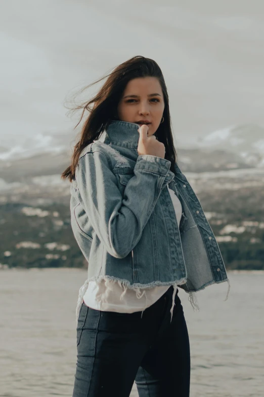 a young woman standing near the water smoking