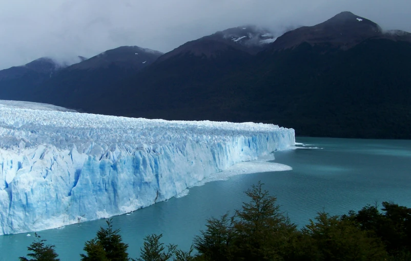 glacier on water with mountain in backround